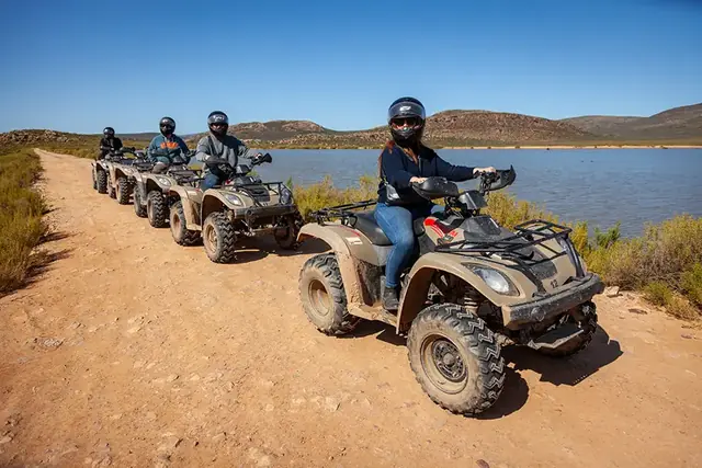 Guests riding quad bikes beside a dam at Aquila